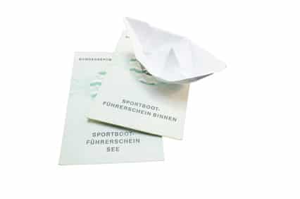 Sportbootsführerschein und ein gefaltetes Boot aus Papier