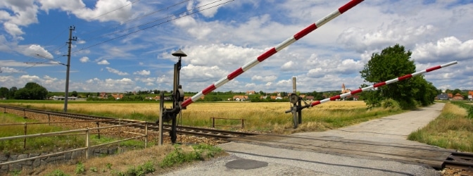 Beschrankter Bahnübergang: Die sich senkenden Schranken weisen darauf hin, dass sich ein Zug nähert.